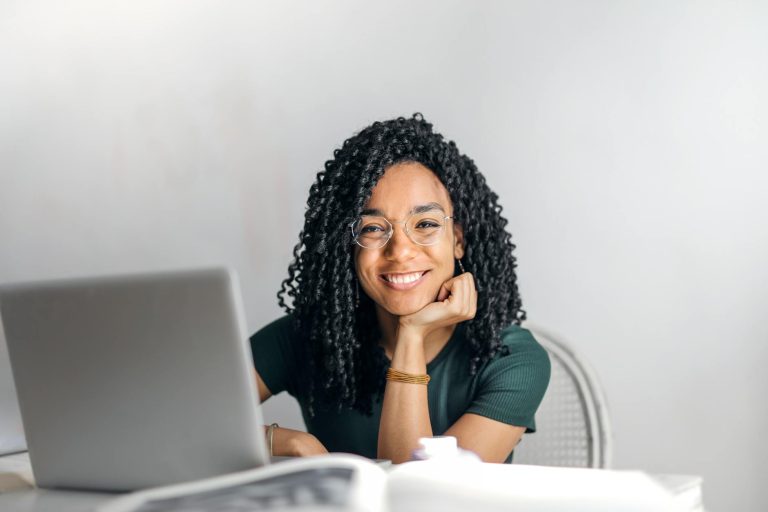 happy ethnic woman sitting at table with laptop doing Freelancing